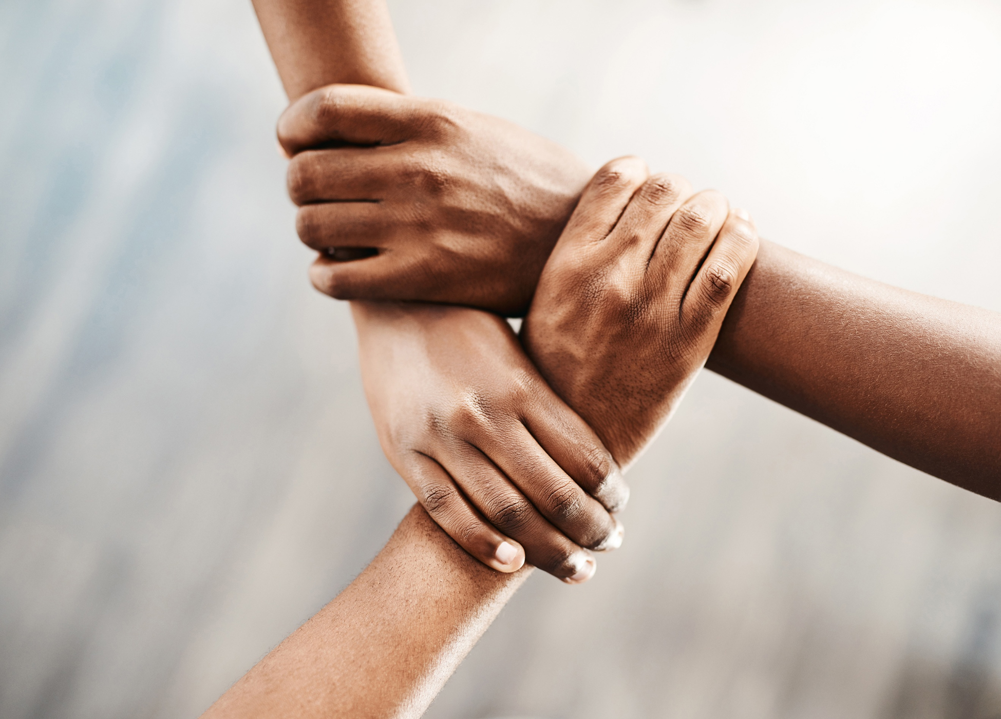 unas manos entrelazadas formando un triángulo simbolizando unión y apoyo